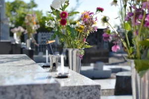 Fleurs fraîches et bougies d'hommage disposées sur une pierre tombale au cimetière.